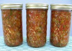 three jars filled with food sitting on top of a blue cloth covered table next to each other