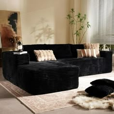 a living room with black couches and rugs on the floor in front of a window