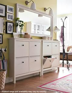 a white dresser sitting next to a living room filled with furniture and pictures on the wall