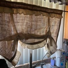 a kitchen with a sink, window and hanging curtains in it's windowsill