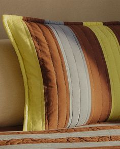 a close up of a pillow on a bed with yellow and brown pillows in the background