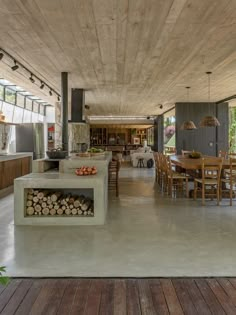 an open kitchen and dining area with wood flooring in the center, surrounded by large windows