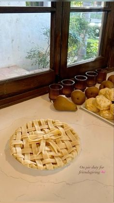 an uncooked pie sitting on top of a counter next to cups and bowls