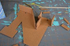 an open cardboard box sitting on top of a table next to some scissors and tape