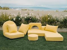 a yellow couch sitting on top of a lush green field