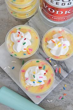 three small desserts with whipped cream and sprinkles on a marble table