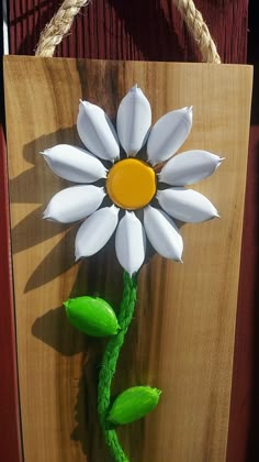 a wooden sign with a white flower on it's side hanging from a rope