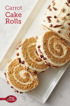 carrot cake rolls with cream cheese frosting and pecans on top, sitting on a white plate