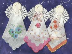 three pieces of cloth with lace on them are hanging from clothes pins in the shape of angel wings