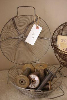 a wire basket with rolls of thread in it next to a clock on the wall