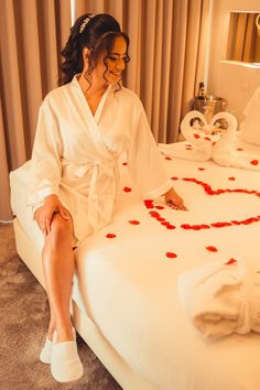 a woman sitting on top of a bed in a hotel room next to two towels