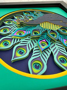 a close up of a peacock design on a green table top with yellow border around the edges