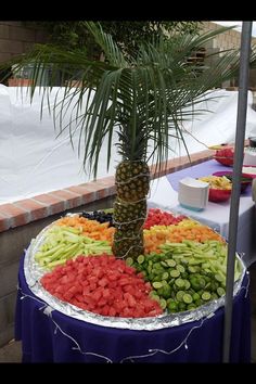 a palm tree in the middle of a table filled with fruits and veggies