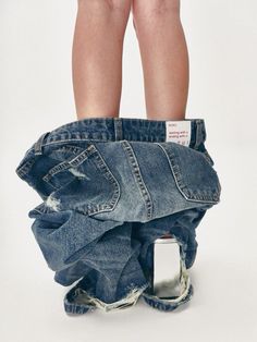 a pair of legs sticking out of an old pair of blue jeans with ripped knees