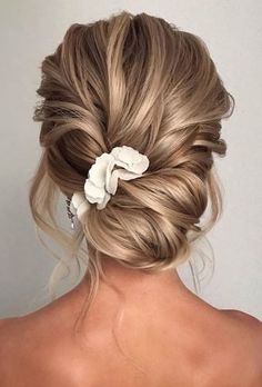 the back of a woman's head with blonde hair and flowers in her hair