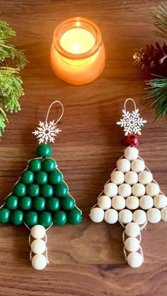 two christmas trees made out of candy are sitting next to a candle and some pine branches