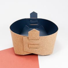 an empty paper bowl on top of a red piece of paper next to a cardboard box