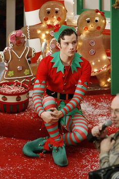 a man sitting on the floor in front of some christmas decorations and gingerbreads