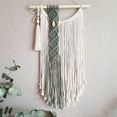 a macrame hanging on a wall next to a potted plant and succulents