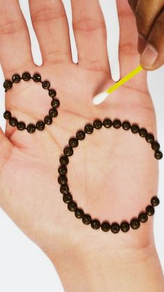 a hand holding a string of beads with a pencil in it