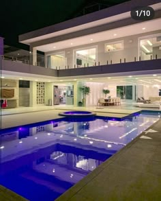 a large house with a swimming pool in the front yard and patio area at night