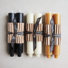 four candles wrapped in brown paper and tied with black ribbon on the wall next to each other