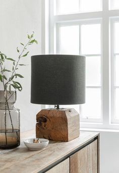 a table with a lamp, bowl and vase on it