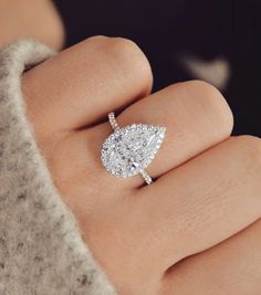 a woman's hand with a diamond ring on top of her finger and an engagement ring in the middle