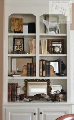 a white bookcase filled with lots of books next to a chair and mirror on top of it