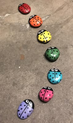 six painted ladybugs lined up in a row on the ground with one laying down