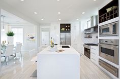 a modern kitchen with stainless steel appliances and white countertops, along with an island in the middle