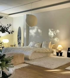 a large white bed sitting in a bedroom next to a tall plant and two lamps