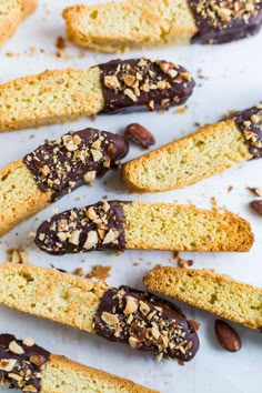 several pieces of bread with chocolate and nuts on top, sitting on a white surface