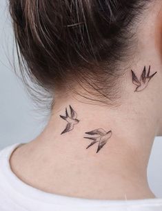 a woman's neck with two small birds on the back of her left ear