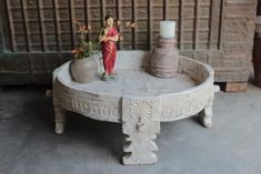 a small figurine sitting on top of a table next to a vase with flowers