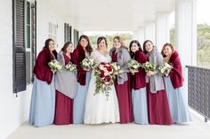 a group of women standing next to each other on a white porch holding bouquets