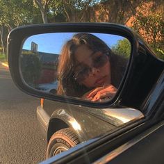 a woman taking a selfie in the side mirror of a car