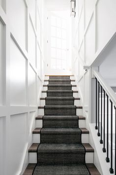 a set of stairs leading up to an open door in a white building with black railings