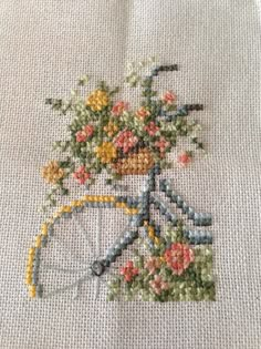 a close up of a cross stitch pattern with a bicycle and flowers on the front