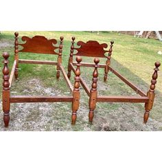 three wooden beds sitting on top of a grass covered field next to each other with headboards and foot boards