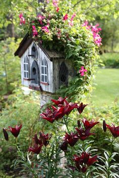 a bird house with flowers growing around it