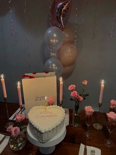 a heart shaped cake on a table with pink roses and silver balloons in the background