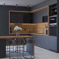 a modern kitchen with an island and bar stools in the center, surrounded by gray cabinets