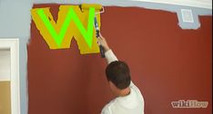 a man is painting the wall with green paint and yellow letters on it that spell out w