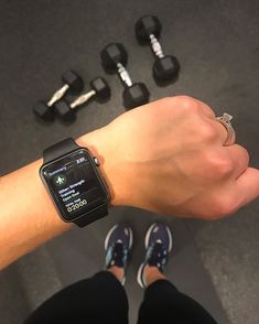 a person's arm with an apple watch on it and dumbs in the background