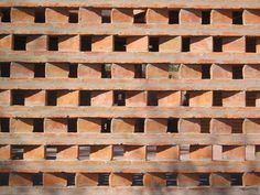 a large brick wall with holes in it's center and two birds perched on top