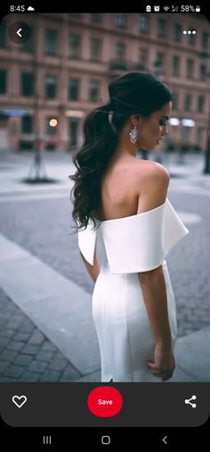 a woman in a white dress is standing on the street with her back to the camera