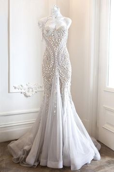 a white wedding dress on display in front of a wall with a mirror behind it