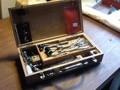 an open wooden box on top of a table filled with different types of electronic devices