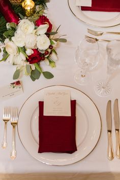 the table is set with red napkins, silverware, and white flowers on it